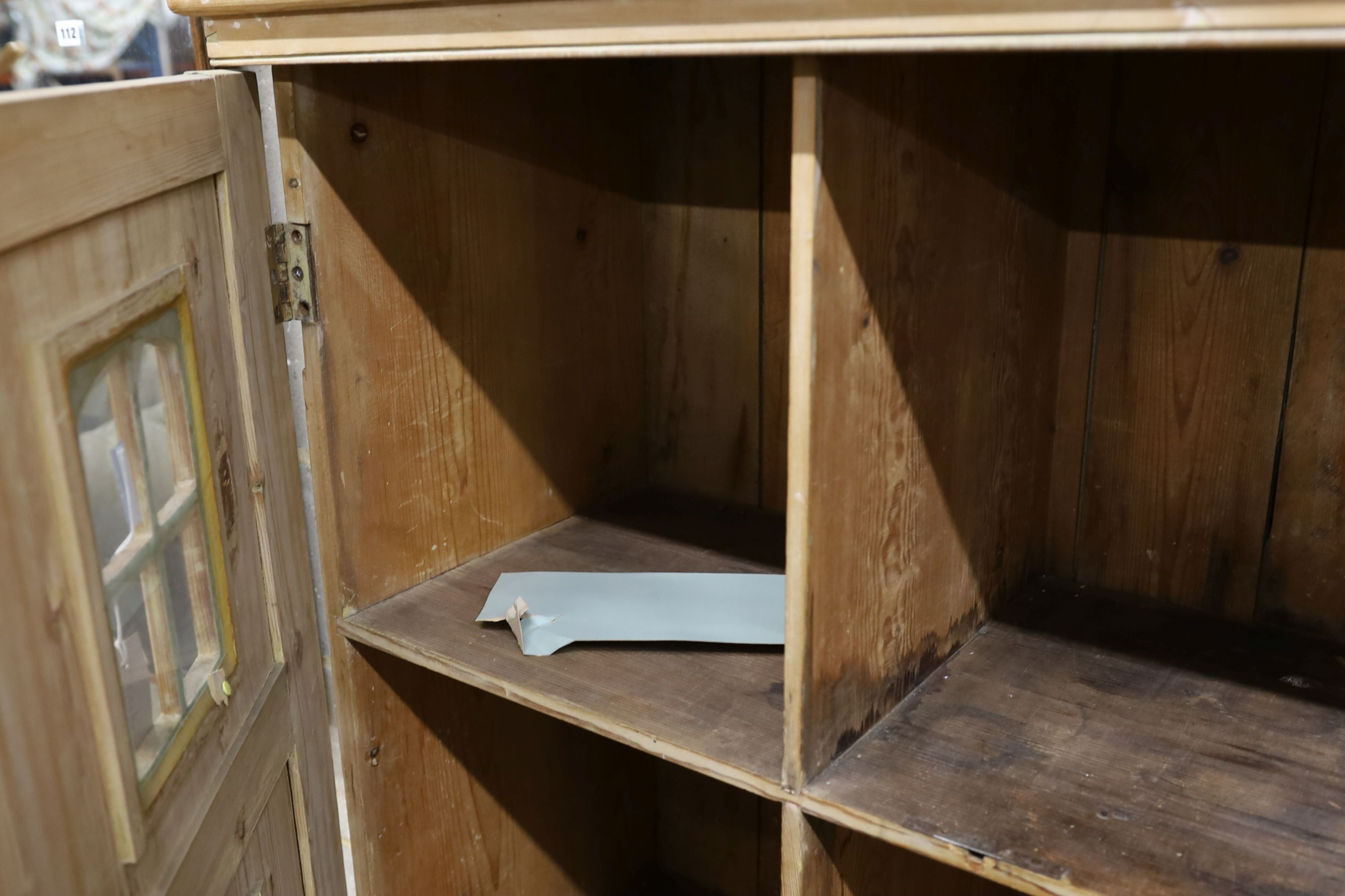 A 19th century stripped pine hall cupboard modelled as a dolls house the two door nine window facade enclosing a compartmented interior, width 182cm, depth 46cm, height 192cm